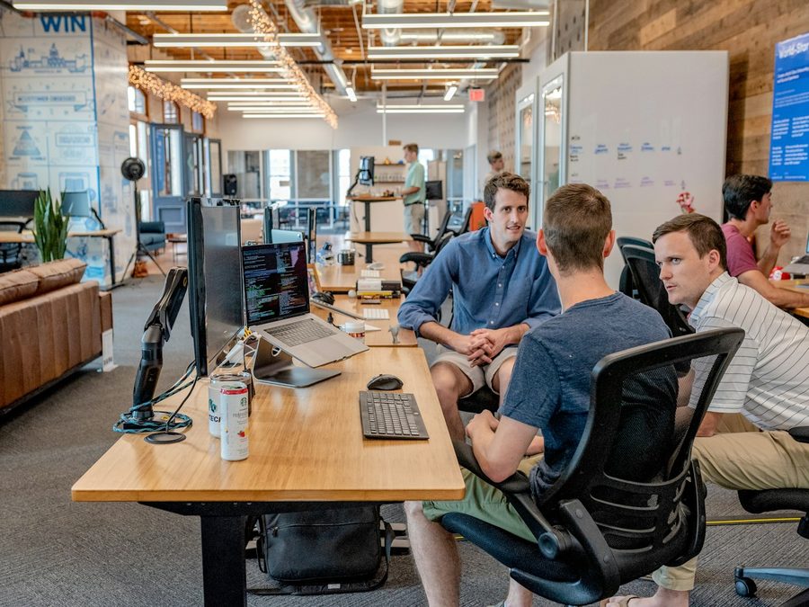 A small team talking around a desk in an open workspace