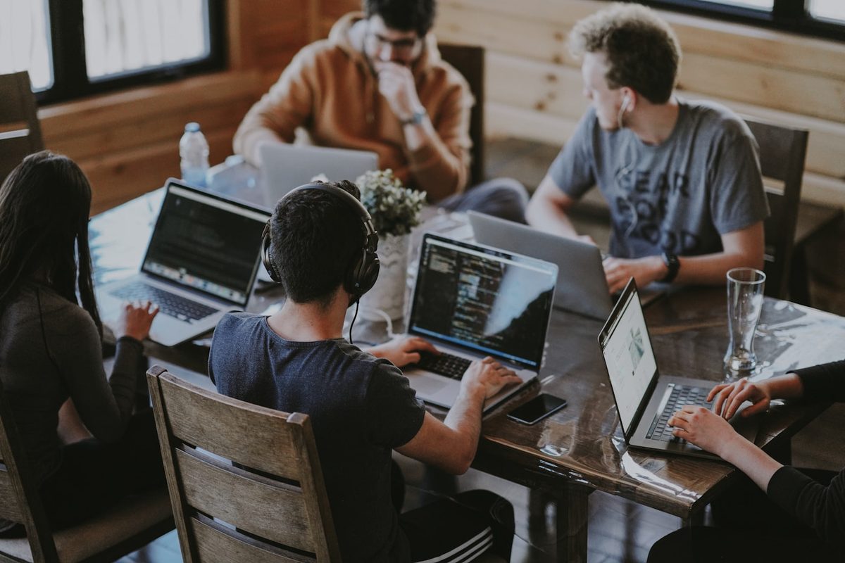 People working together on laptops at a shared wooden table